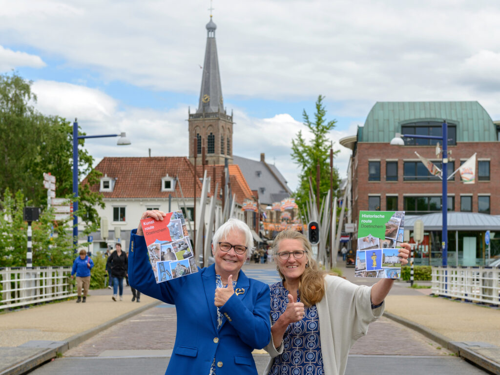 Wilma Lankhorst (links) en Saskia Bruil (rechts) tonen enthousiast de blow ups van de twee stadswandelingen door Doetinchem © foto Jeroen Peters